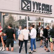 A group of people stand outside the front door of YYC Cycle.